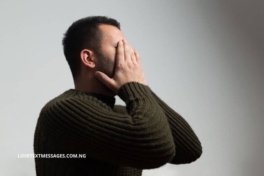 Man in sweater with his face in his hands.